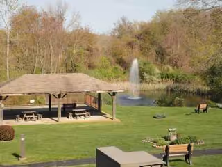 Outdoor park area with gazebo, fountain, benches, and grassy lawn.