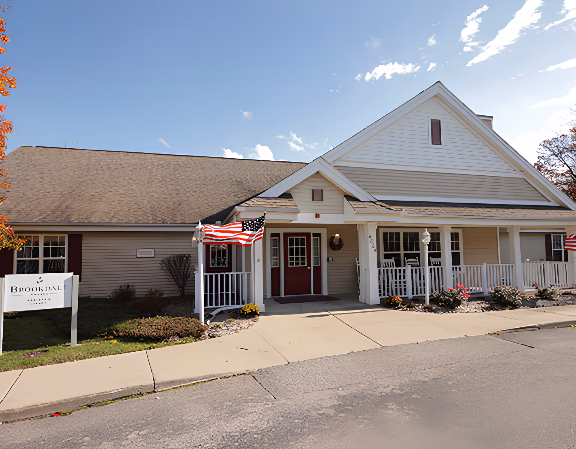 Front exterior of Brookdale Midland showing a single-story building with a covered porch, American flags, and a sign.