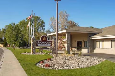 Front entrance of Life Care Center of Richland with flags and a landscaped front area.