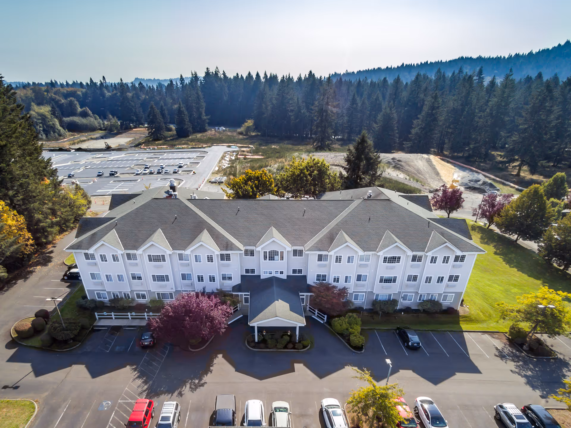 Aerial view of a three-story assisted living building with a parking lot and surrounding trees.