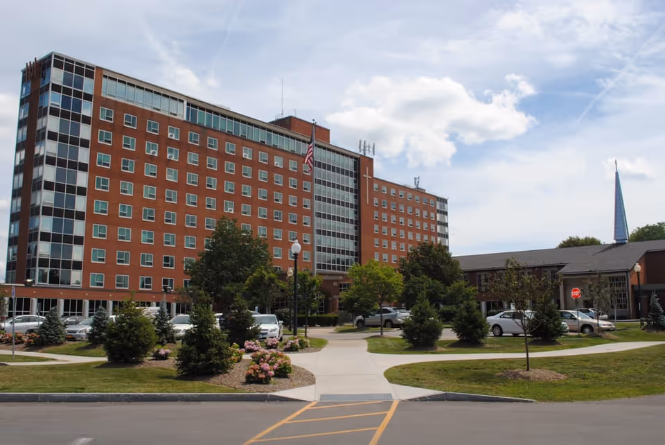 Exterior view of a brick senior living building with parking and landscaping