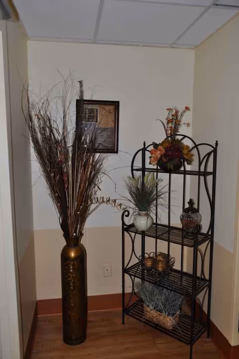 Interior corner featuring a metal shelving unit with vases and dried arrangements.