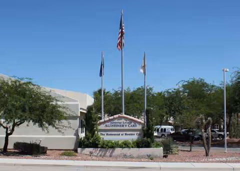 The Homestead at Boulder City sign in front of a light building with flagpoles.