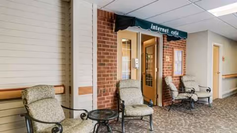 Interior corridor with brick wall, Internet cafe sign, and cushioned chairs along carpet.