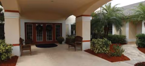 Entrance of Brookdale Fort Myers the Colony with a covered walkway and benches.