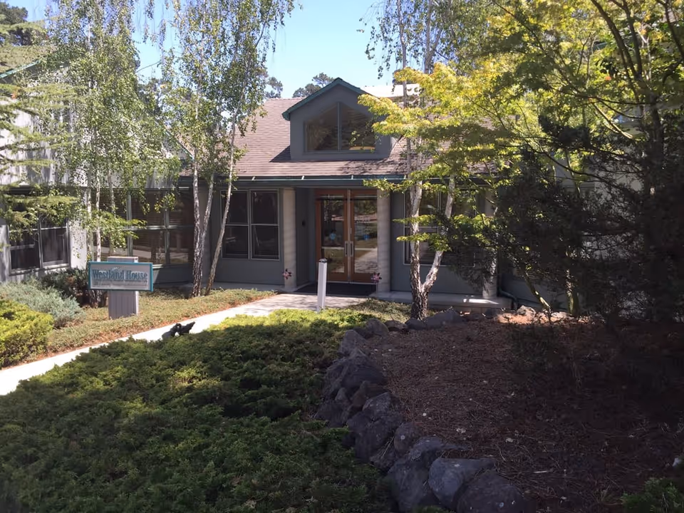 Front entrance of the Westland House building surrounded by trees and landscaping.