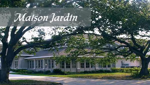 Front view of Maison Jardin Living Community building with trees and driveway.