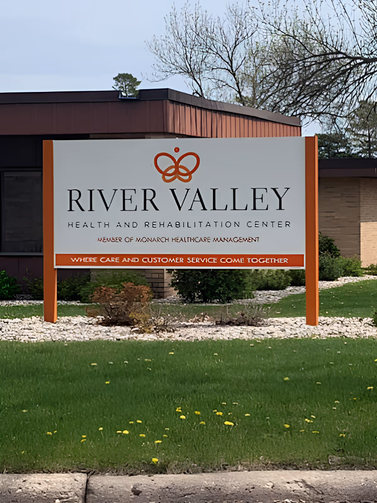 Freestanding sign reading "River Valley Health and Rehabilitation Center" stands on a grassy lawn in front of a low brick building.