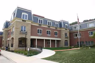 Exterior view of Bethany Home Retirement Center with brick facade, arched entrance, and lawn.