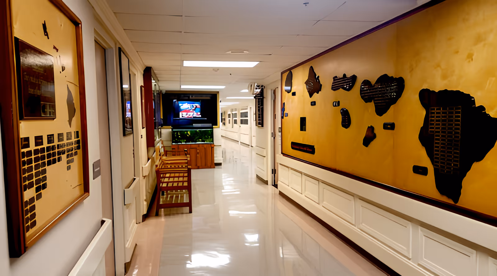 Bright, polished hallway in a nursing facility with benches, a large decorative wall map, and a TV at the end.