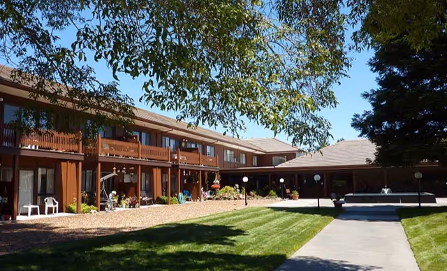 Valley Orchards Retirement two-story building with a grassy courtyard, walkway, and outdoor seating.