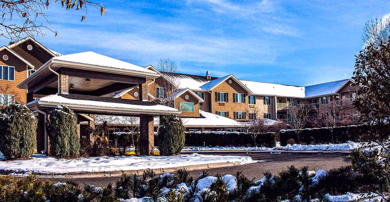 Snowy exterior view of Lodge at White Bear with a covered entrance and driveway.