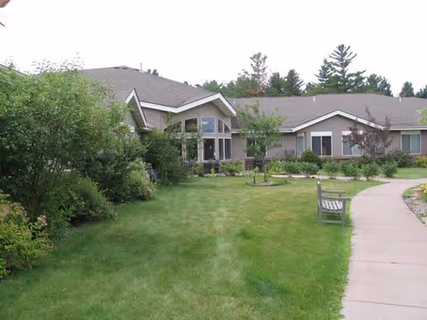 Exterior view of Inter-Faith Care Center with a green lawn, trees, and a curved walkway.