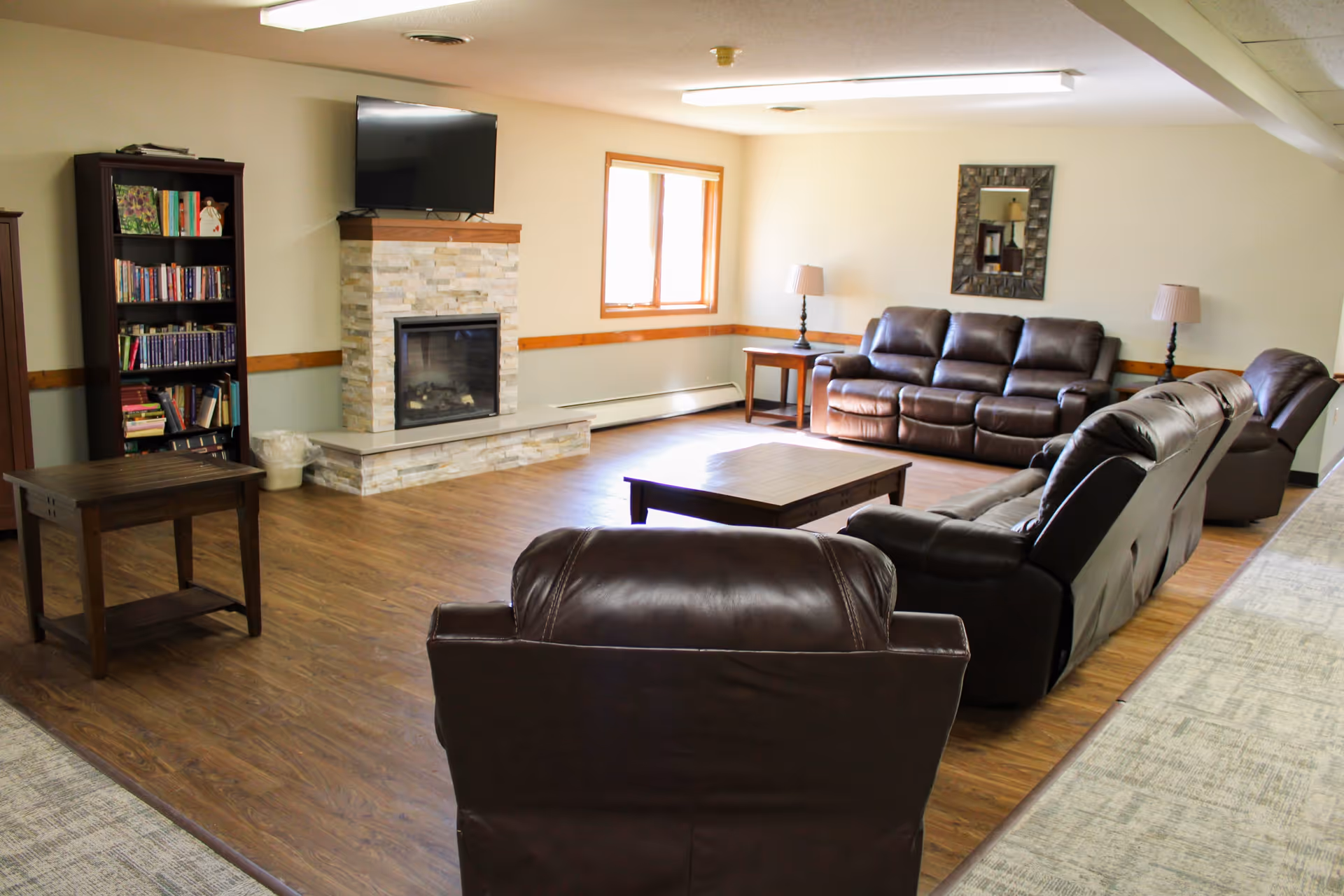 Cozy living room area with seating, table, and a fireplace in a senior living facility.