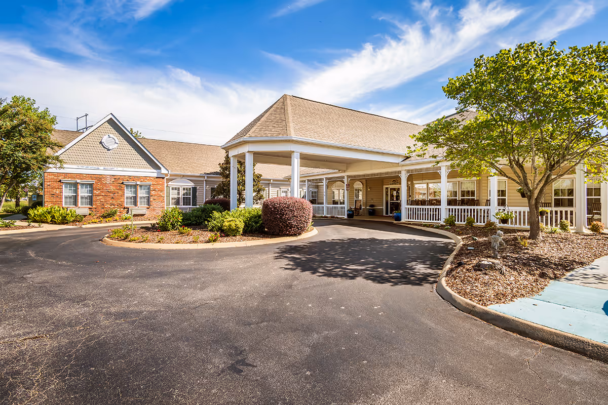 Exterior view of The Neighborhood at Madison entrance with a covered drive and landscaping