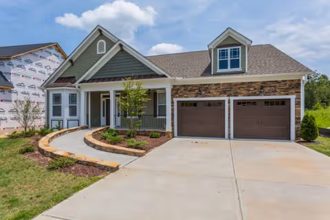 Modern single-story house with a two-car garage, curved walkway, and landscaped front yard.