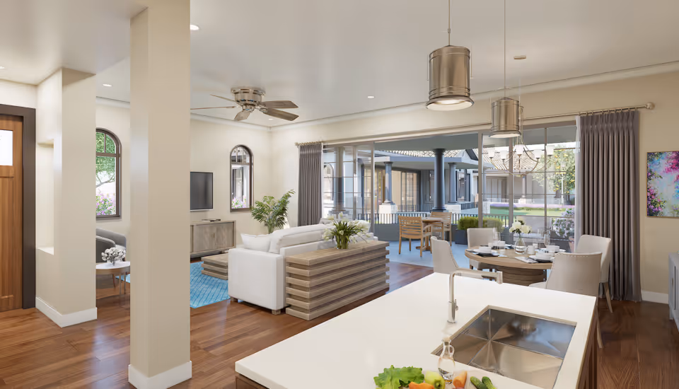 Open-plan, well-lit interior with a kitchen island in the foreground, a living room and dining area, and large sliding glass doors opening to a patio.