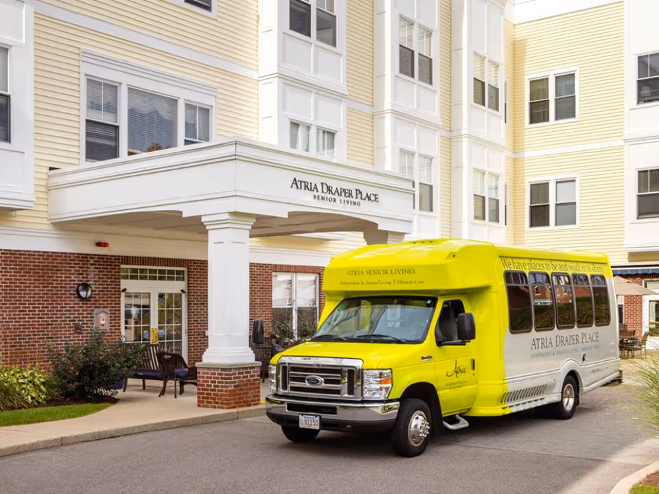 Bright yellow shuttle bus in front of Atria Draper Place entrance.