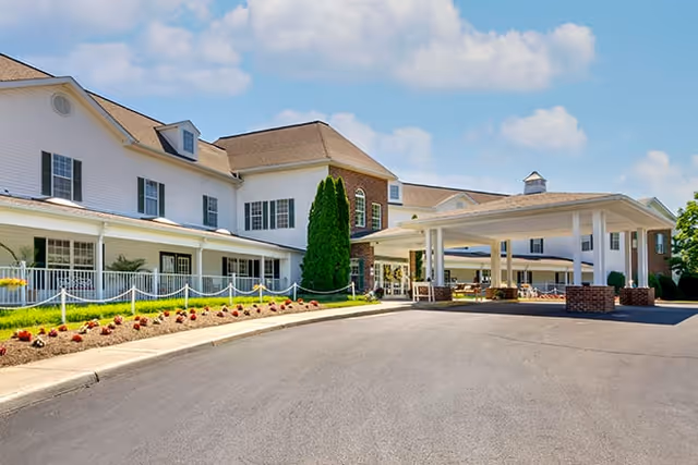 Front exterior of Brookdale Salem featuring a white multi-story building with a covered drop-off portico, driveway, and landscaped flower beds.