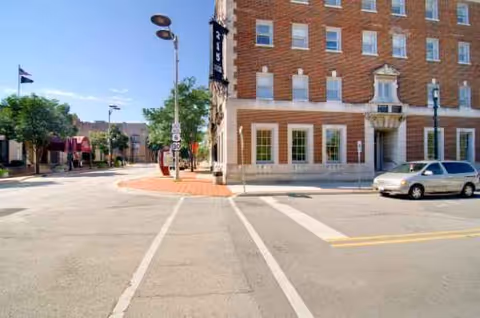 Corner street view of a brick building with a Senior Suites of Joliet sign