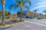Exterior view of The Orchards Senior Living with palm trees, signage, and a parking lot.