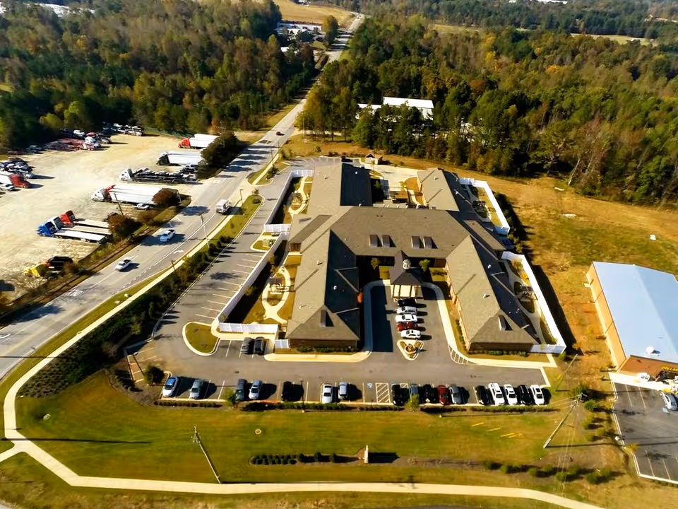 Aerial view of the Hope Center Memory Care facility showing the building, parking lots, driveways, and surrounding trees.