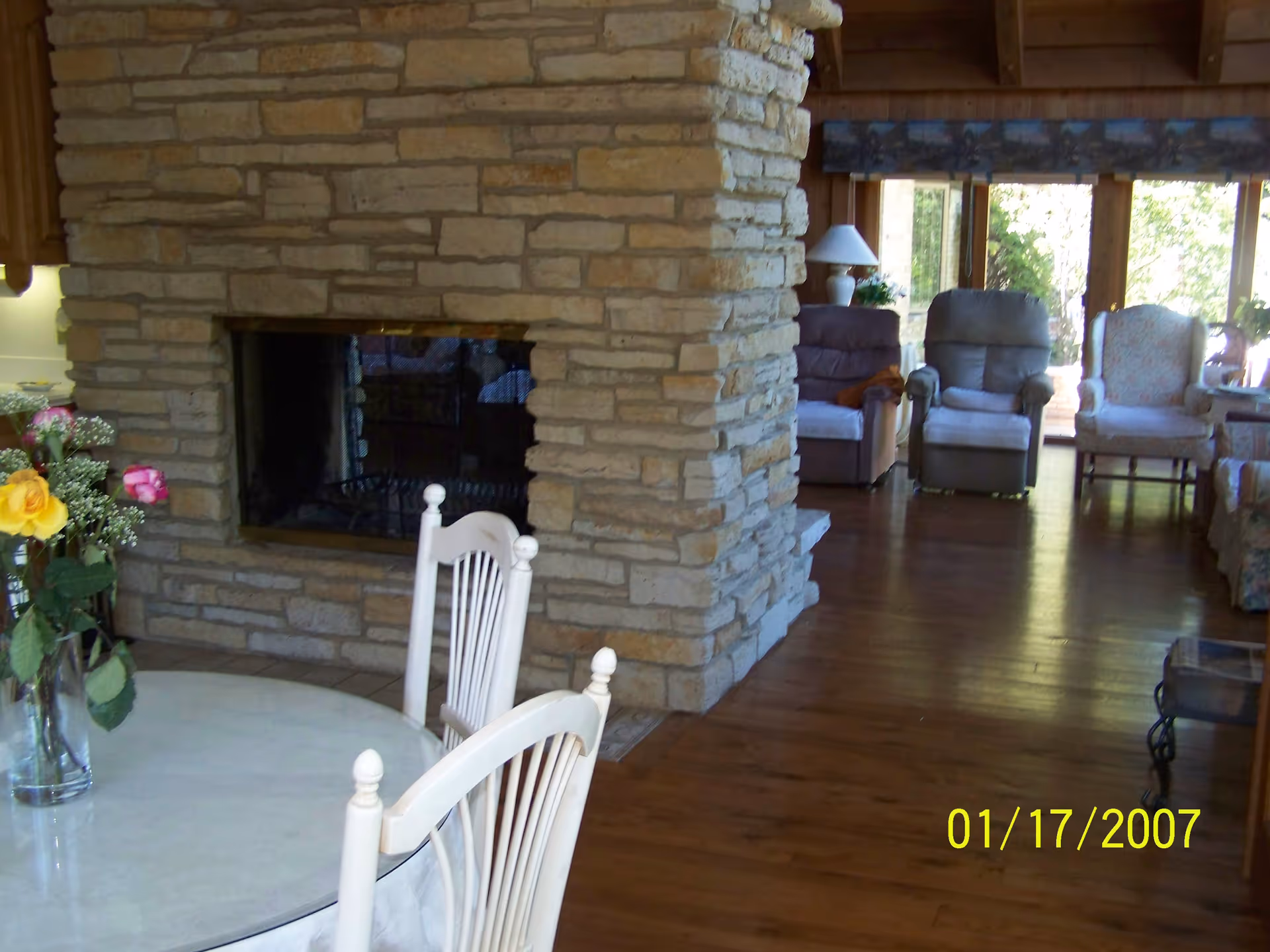 Stone fireplace anchors a spacious living room with chairs and a round table.