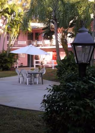 Outdoor courtyard at Midway Manor ALF with table, chairs, umbrella, pink building.