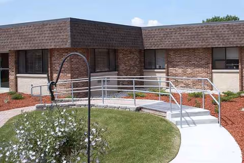 Front view of Maple Ridge Health Services brick facility with a curved ramp and landscaped walkway.