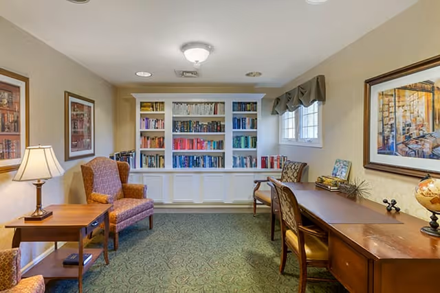 Cozy reading room with built-in bookshelves, upholstered armchairs, and a wooden desk.