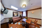 Small communal living room with a sofa, table and chairs, a wall-mounted TV, plants and a skylight.