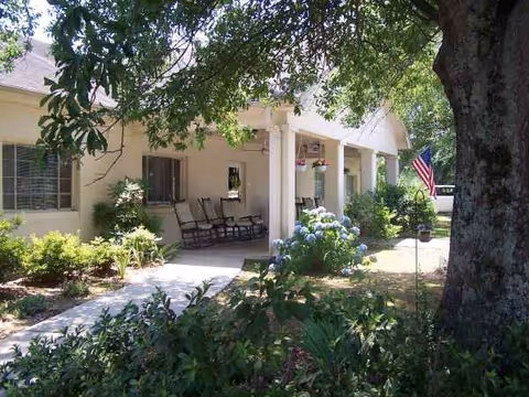 Front porch of Lakeview Assisted Living with chairs, plants, and an American flag.