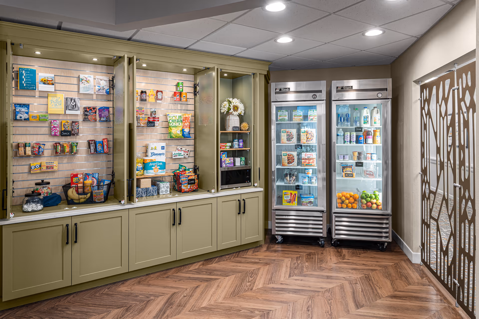 On-site market area with glass-front refrigerated cases and cabinets displaying snacks, beverages, and packaged goods.