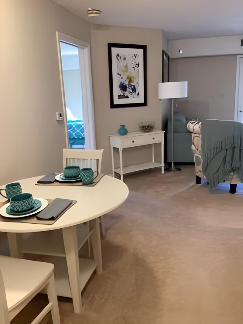 Open living and dining area with a round table set with teal dishes, a console table, floor lamp, and sofa.