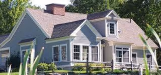 Exterior view of Falmouth House at OceanView, a light-blue senior living residence with porch.