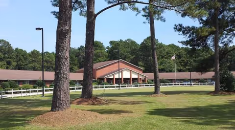 Exterior view of Castle Creek Memory Care building with lawn, trees, and flag.