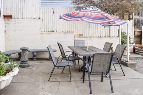 Outdoor patio with a table, several chairs, and a striped umbrella.