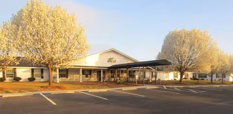 Front view of Rolling Ridge facility with parking lot, entrance canopy, and trees.