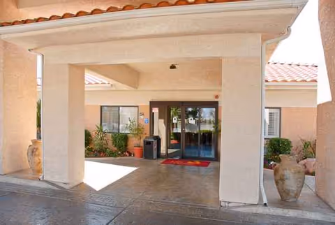 Exterior entrance of Life Care Center of Las Vegas with columns and planters.