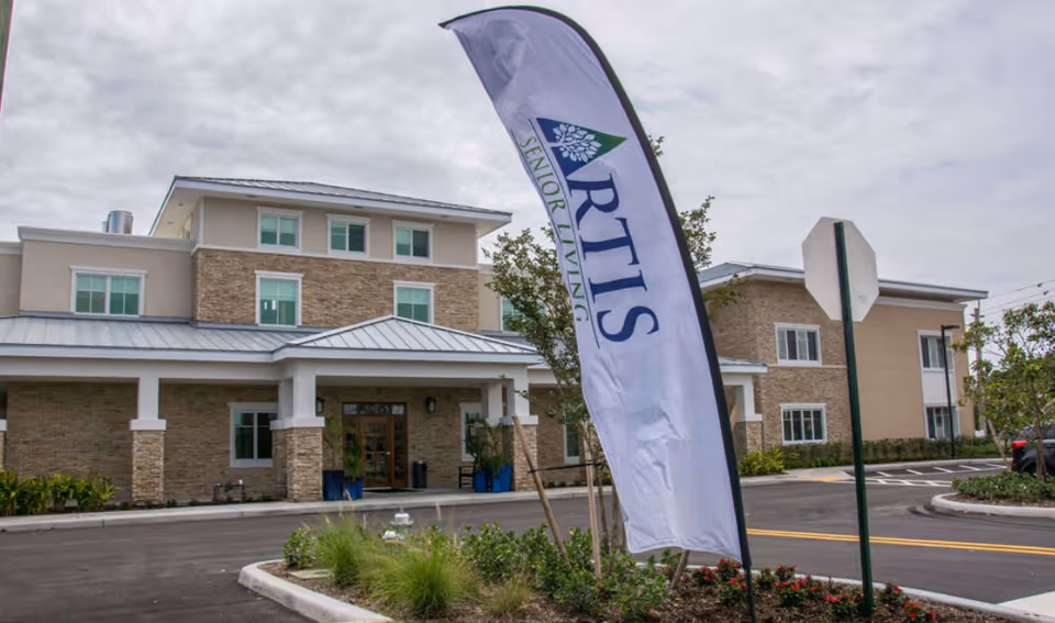Front exterior of Artis Senior Living of Boca Raton with a tall banner.