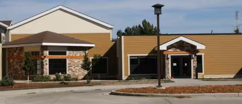 Exterior view of a single-story senior living facility with an entrance and parking area.