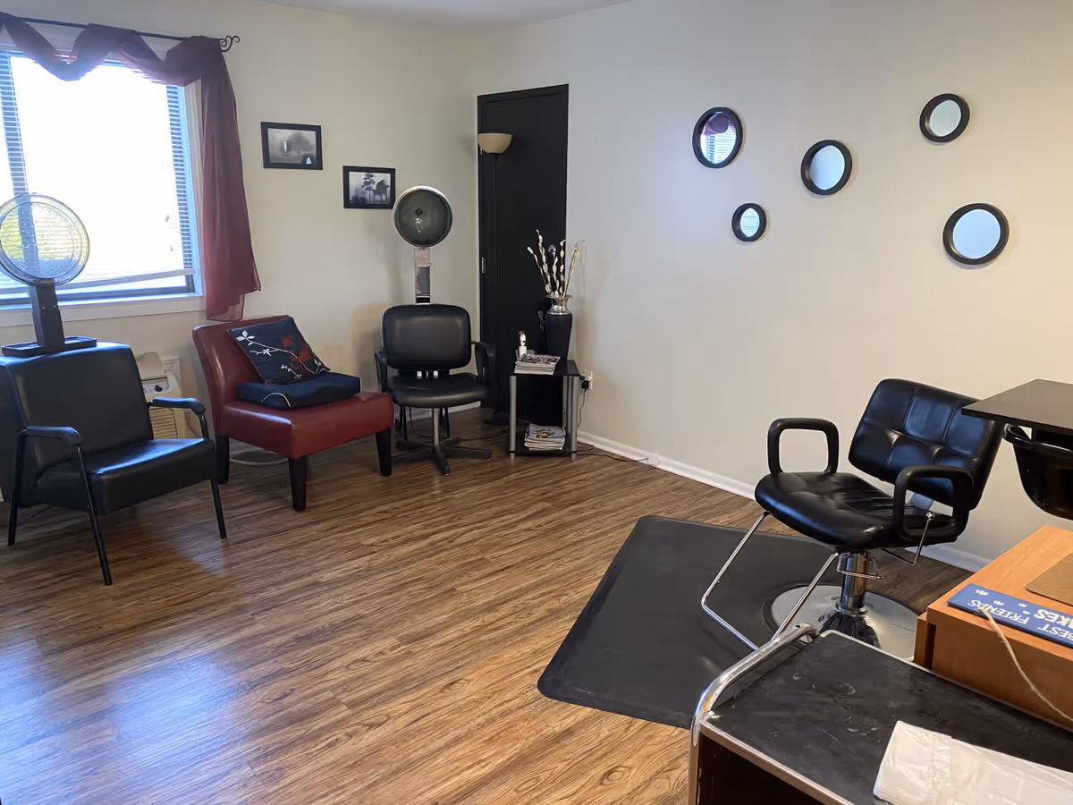 Small salon or styling room with multiple chairs, a hooded hair dryer, round wall mirrors, and wood-look flooring.