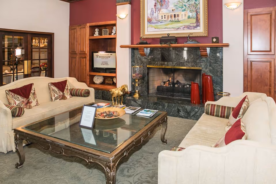 Cozy lounge with two sofas facing a glass-topped coffee table and a marble fireplace.