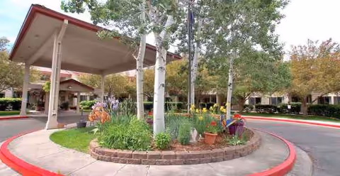 Exterior view of a facility entrance with a circular planted island and covered drop off area.