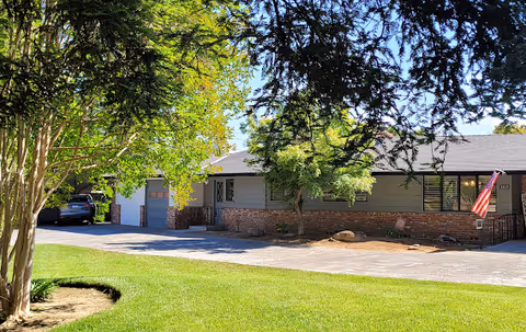 Exterior view of Evergreen Life Care Homes building with trees, lawn, and driveway.