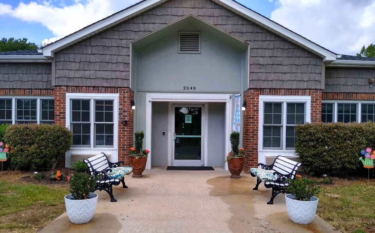 Front entrance of a single-story brick building with benches, potted plants, and the address 2040 above the doorway.
