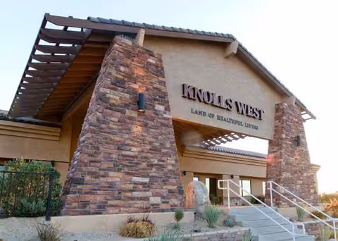 Exterior view of Knolls West Residential Care entrance with stone pillars and sign.