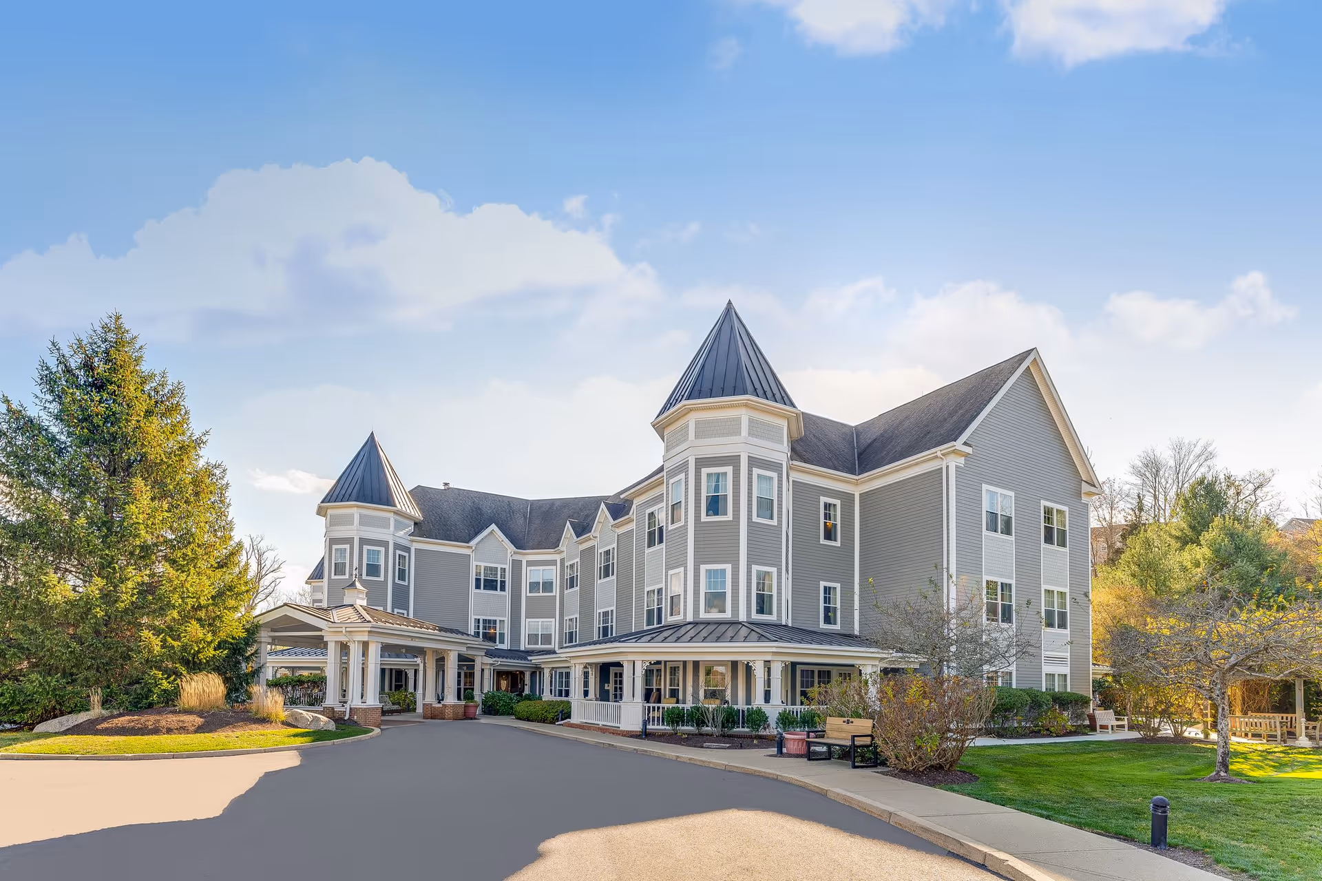Grey multi-wing Sunrise of Cohasset senior living building with turreted roofs.