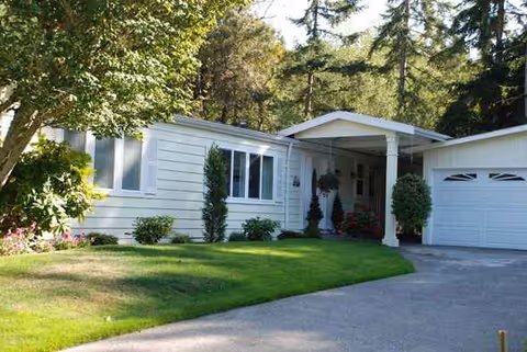 Front exterior of a single-story light-colored home with a green lawn and driveway.