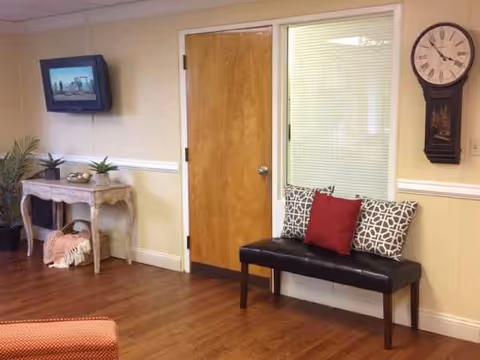 Interior common area with bench seating, wooden door, wall-mounted TV, and clock.